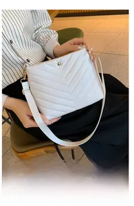 Close-up of white PU leather bucket bag with V-shaped quilting and gold metal buckle