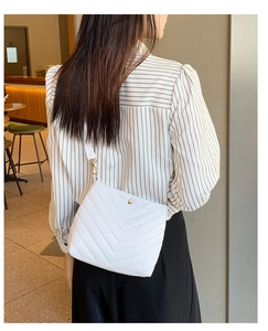 Detail of white PU leather bucket bag with V-shaped quilting and gold metal hardware clasp