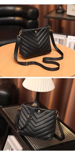 Detail of black quilted faux leather crossbody bucket bag with V-shaped stitching and gold hardware