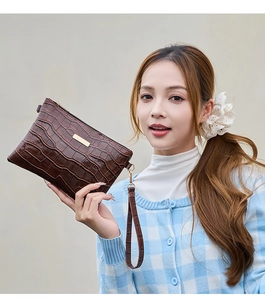 Detail der dunkelbraunen Handtasche mit Steinmuster, Goldbeschlägen und Schlaufe