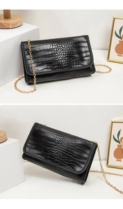 Detail der schwarzen Krokodil-Strukturtasche mit eleganter goldener Metallkette