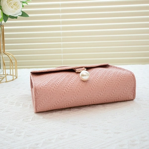 Pink woven crossbody bag with elegant pearl pendant and textured chevron pattern