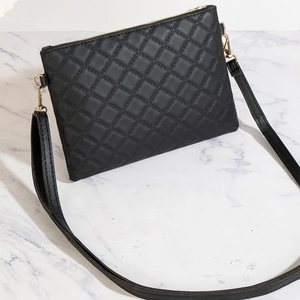 Detail of black quilted leather shoulder bag with fine stitching and gold zipper hardware