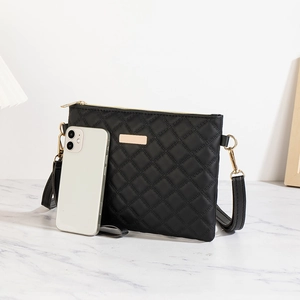 Detailed view of black quilted crossbody bag with gold hardware and size comparison