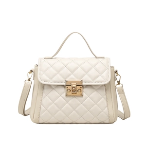 Quilted cream kelly bag with gold hardware and top handle in a minimalist style