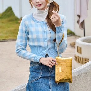 Elegant gold faux leather clutch with crocodile pattern and wrist strap held by model