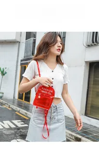 Détail du mini sac à dos en PVC rouge transparent avec lettrage blanc et pendentif doré
