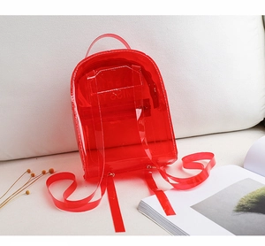 Détail du sac à dos rouge transparent en PVC avec poignée supérieure et fines bretelles
