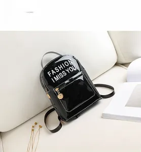 Détail d'un mini sac à dos en cuir verni noir avec slogan blanc et fermetures éclair dorées