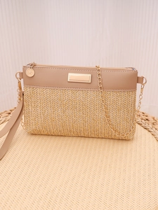 Detail of woven straw and beige leather shoulder bag with gold chain and metal plaque