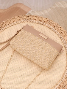 Detail of beige woven straw envelope bag with leather trim and gold chain strap
