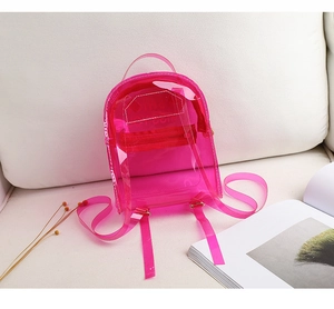 Détail du sac à dos transparent en PVC rose avec bretelles sur un canapé blanc