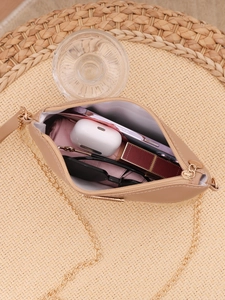 Detail of beige woven crossbody bag showing compact storage with phone and essentials