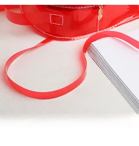 Détail de la bandoulière en PVC rouge transparent avec bords lisses et couture soignée
