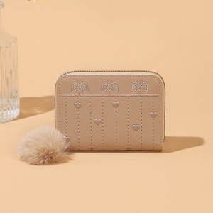 Dettagli dei ricami a cuore e farfalla su un portafoglio in pelle PU beige con zip