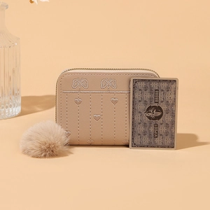 Dettaglio portafoglio corto beige con cerniera per donna con ricamo cuore e pompon