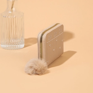Dettaglio mini portafoglio beige con ricamo a cuore e morbido ciondolo a pompon