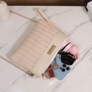 Detail view of woven shoulder bag showing interior capacity with phone and sunglasses