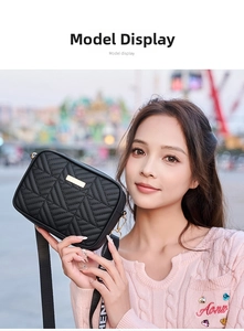 Detalle del bolso de cámara acolchado en V negro con logo dorado y correa de jacquard