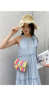 Detalle de bolso bandolera de paja con rayas de colores y cadena dorada en modelo