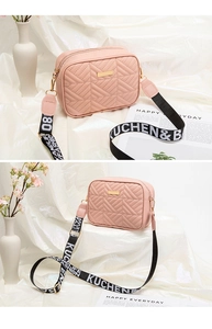 Detalle de bolso acolchado rosa con correa ancha de tela tejida con texto decorativo