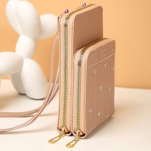 Détail de la pochette téléphone rose clair avec broderies cœur et nœud et double fermeture