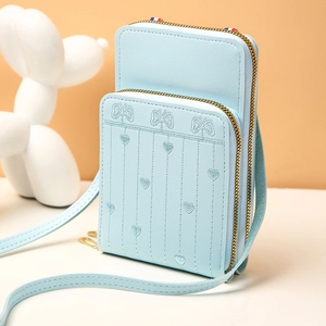 Détail du sac à téléphone en cuir bleu clair avec broderie papillon et deux fermetures