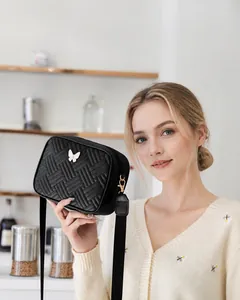 Detalle de bolso bandolera acolchado con hebilla de mariposa blanca y textura tejida