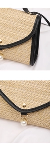 Detailed view of straw square bag with pearl pendant and black leather trim