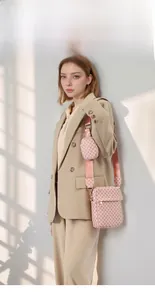 Close-up of pink monogram shoulder bag with matching round coin purse and wide strap