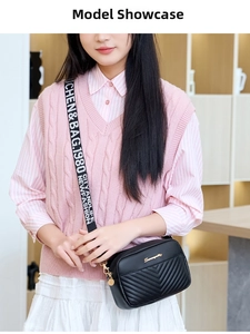 Close-up of black quilted crossbody bag with V-shaped stitching and wide jacquard strap