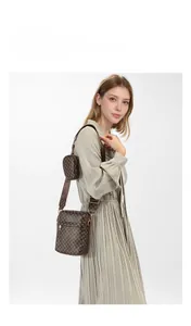 Detailed view of dark brown monogram shoulder bag with matching round coin purse on a model