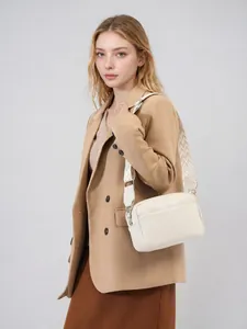 Detail van de witte kiezellederen crossbodytas met een brede geweven schouderband