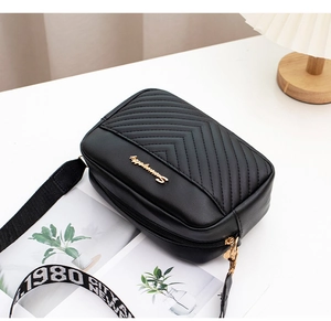 Close-up of black quilted camera bag with gold logo and 1980 CITY NEW YORK woven strap