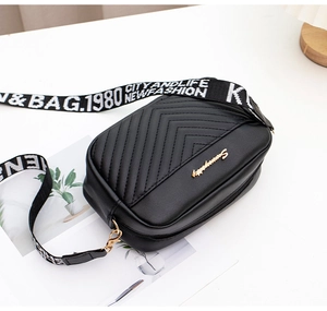 Detail of black quilted crossbody bag with chevron stitching and stylish letter strap