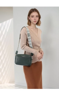 Dettaglio borsa a tracolla in pelle verde scuro con tracolla larga geometrica su modella