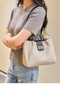 Detail of straw woven tote bag with black leather flap and gold chain strap on model