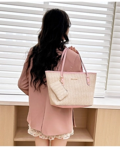 Detail of a woven straw tote with pink leather straps and a matching small purse charm
