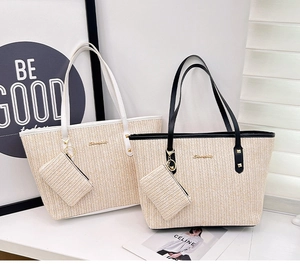 Detail view of woven straw tote bags with leather handles and matching small pouch