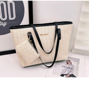 Detail of woven beige straw tote bag with black leather straps and gold metal logo