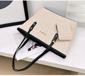 Detail of woven straw tote bag set with black leather trim and small clutch on display