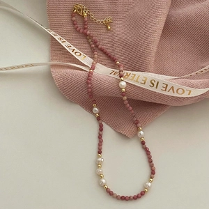 Gros plan du collier en pierre naturelle rose avec perles d'eau douce et détails dorés fins