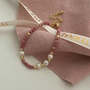 Détail macro de collier perles d'eau douce et pierre rose avec fermoir doré