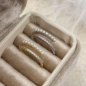 Close-up of double-layered open rings with white pearls and sparkling zircon accents