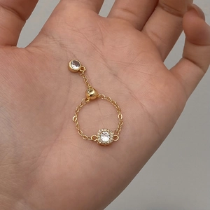 Detail of adjustable 18K gold chain ring with sparkling round zircon and pull-clasp design