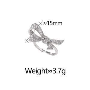 Detail of micro-set zircon bow ring showing 15mm dimensions and adjustable silver band