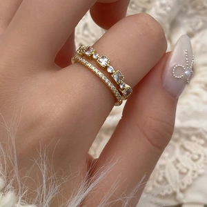 Close-up of stacked gold-plated rings featuring micro-pave zircons on a lace background
