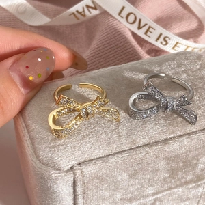 Exquisite gold and silver bow rings with pavé cubic zirconia in a velvet jewelry box
