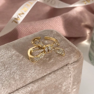 Close-up of golden bow ring with micro-pave zircons on champagne velvet gift box