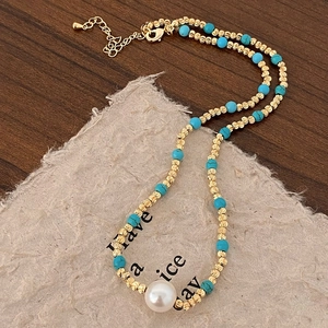 Détail du collier fait main avec des perles de turquoise, des accents dorés et une perle
